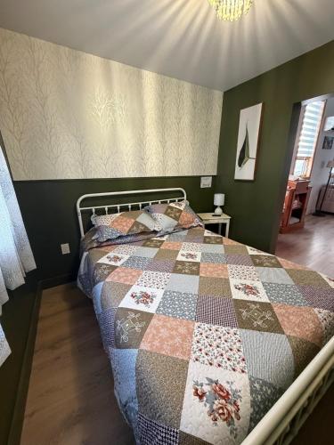 a bedroom with a bed with a quilt on it at A Stay Across The Bay in Curling
