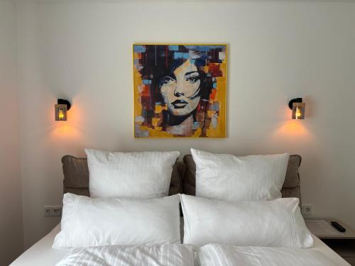 a bed with white pillows and a painting on the wall at Hygge in Neumünster