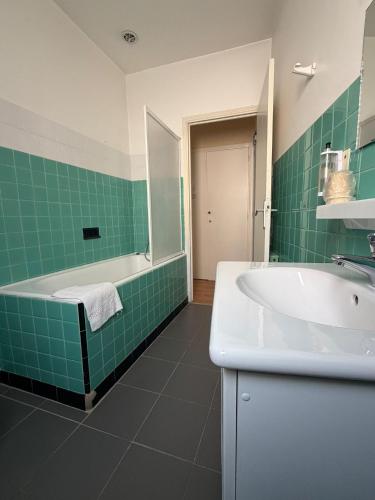 a bathroom with a sink and a tub and green tile at Hôtel du Commerce - Centre Millau in Millau