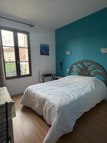 a bedroom with a large bed with a blue wall at Hôtel du Commerce - Centre Millau in Millau