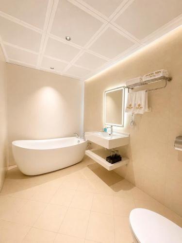 a white bathroom with a tub and a sink at Giang Son Hanoi Hotel in Hanoi