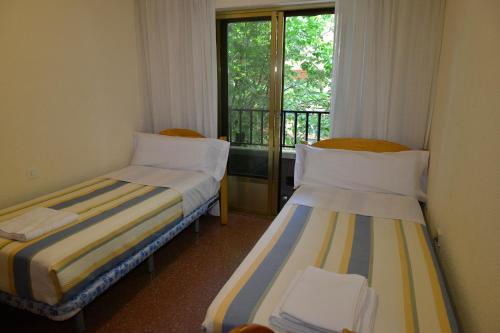 two beds in a room with a window at Casa Noël in Puertollano