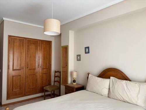 a bedroom with a bed and a wooden cabinet at Brisa do Mar in Vagos
