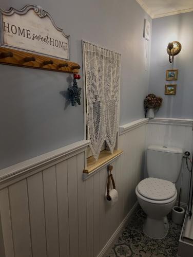 a bathroom with a toilet and a home sweet home sign at Dębowy Zakątek in Dębowo
