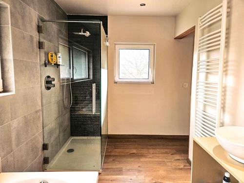 a bathroom with a glass shower and a sink at Modern Spacious Forest Home in Aywaille