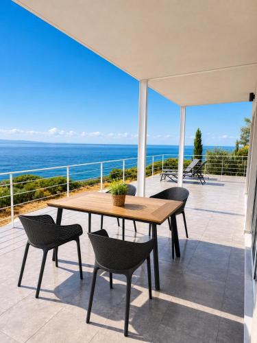 a wooden table and chairs on a patio with the ocean at Thalasson Beach House in Koroni