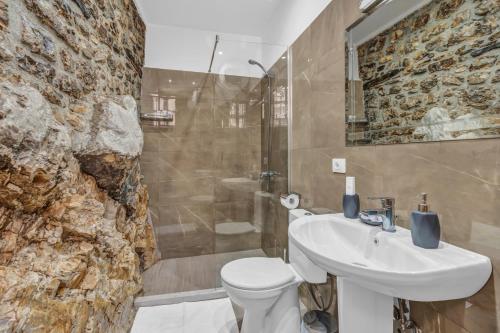 a bathroom with a sink toilet and a stone wall at Guest House J.Prifti in Berat