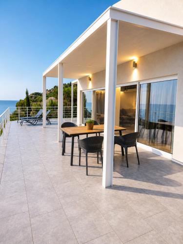 a patio with a table and chairs and the ocean at Thalasson Beach House in Koroni