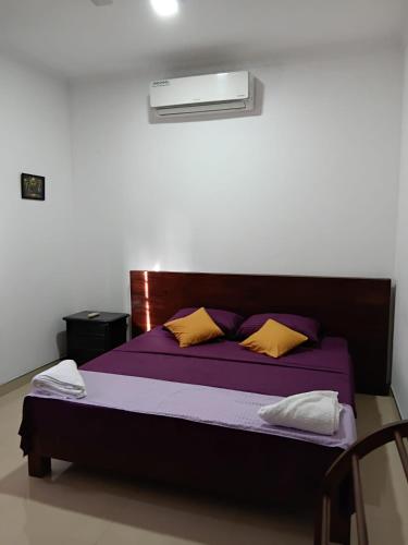 a bedroom with a bed with purple sheets and yellow pillows at Muthu Villa in Negombo