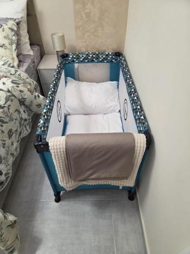 a blue crib with a pillow in a bedroom at Golden Time SM Apartman in Sremska Mitrovica