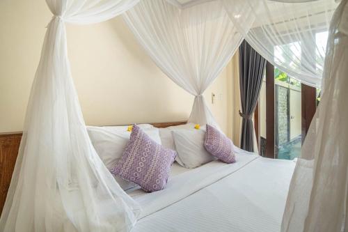a bedroom with a white canopy bed with purple pillows at D'nala Villa - 4 bedroom villa in Lebih
