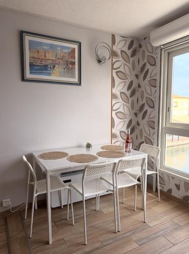 a dining room with a white table and chairs at Studio cosy climatisé vue sur port in Cap d'Agde