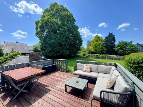 eine Terrasse mit Sofa und Tisch auf einem Deck in der Unterkunft Le BrasÔvert in Bras