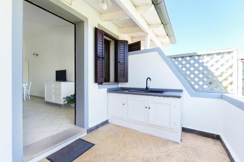 a white kitchen with a sink and a staircase at Residence con piscina Piricone in Orosei