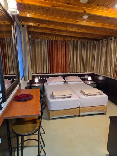 a bedroom with two beds and a table and a desk at Shefer Guesthouse in Eilat