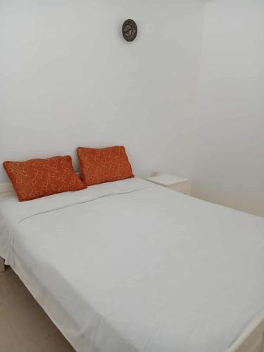 a white bed with two orange pillows on it at Appartement Détente Hammamet in Hammamet