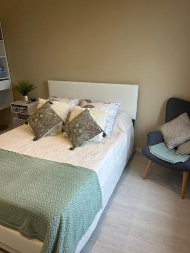 a bed with two pillows and a chair in a bedroom at Chez TIKA in Saint-Lager