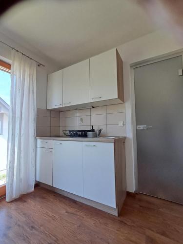 an empty kitchen with white cabinets and a window at Mountain view in Medvode