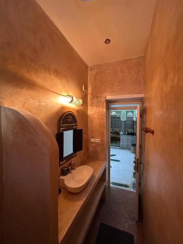 a bathroom with a sink and a tv on the wall at Riad Dar Lina Logement entier in Rabat
