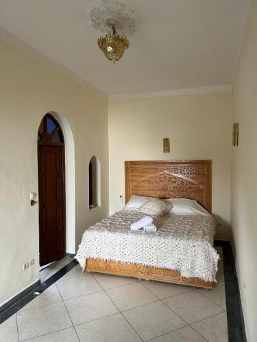a bedroom with a large bed with a wooden headboard at Riad Dar Lina Logement entier in Rabat