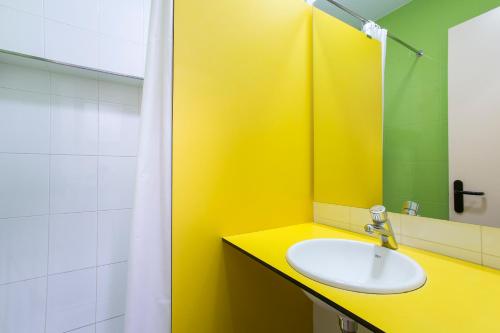 La salle de bains jaune est pourvue d'un lavabo et d'un miroir. dans l'établissement Alberg Santa Maria del Roure, à Cantonigros