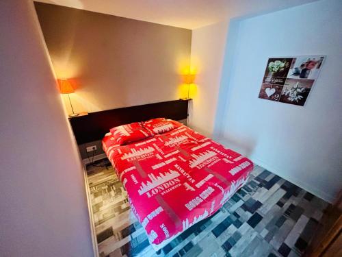 a bedroom with a red comforter on a bed at Le cosy - T2 52m2 - Proche Gare TGV et RCEA in Le Breuil