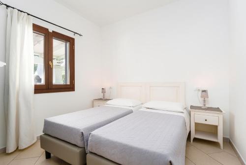 two beds in a white room with a window at Residence con piscina Piricone in Orosei