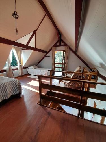 a room with a bed and a table in a attic at Chalé Terra Nova in Itamonte