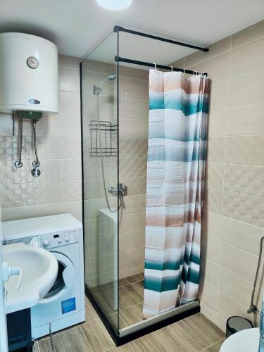 a bathroom with a shower and a sink and a washing machine at Sutorange in Sutomore
