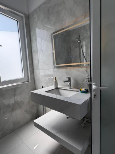 a bathroom with a sink and a window at Villa Thalassa Lal'Andrea in Dhërmi