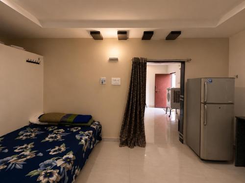 a bedroom with a bed and a refrigerator in it at Hotel Moturi Farmstay Vemulawada in Vemalwāda