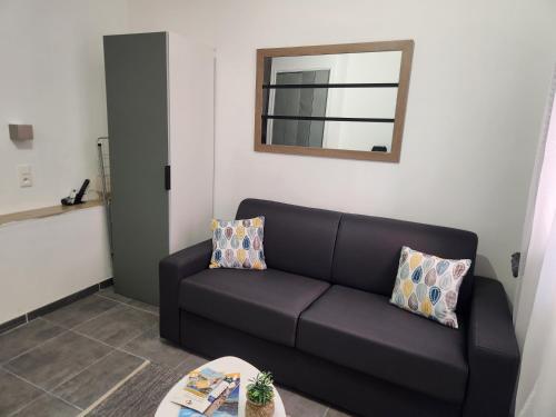 a black couch in a living room with a mirror at Studio proche de la mer in Calvi
