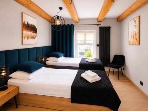 two beds in a room with blue curtains at Apartament Rynek Szmaragd in Szamotuły