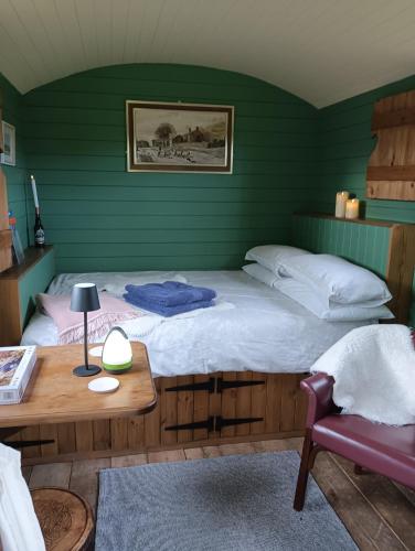 a bedroom with a large bed and a wooden table at Lucker mill shepherds huts in Lucker