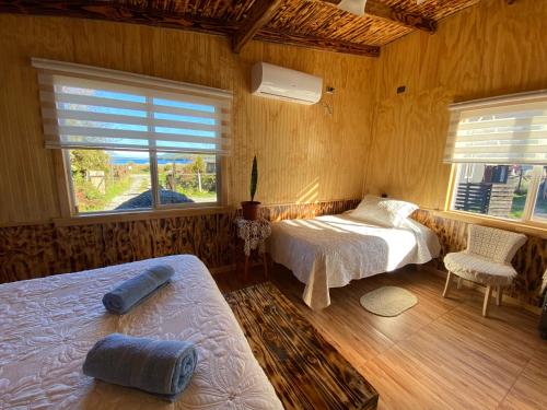 a bedroom with two beds and two windows at Departamentos Eldestino in Puerto Puyuhuapi