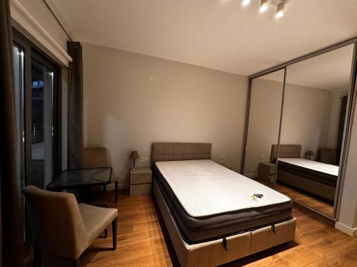a bedroom with a bed and a chair and a mirror at Serenity De Lluxe in Kavač