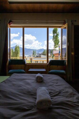 a bed in a room with a large window at Chandan Guest House in Leh