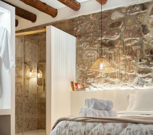 a bedroom with a stone wall with a shower at ruralhomemora in Mora de Rubielos