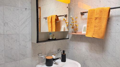 a bathroom with a sink and a mirror and yellow towels at Golden Boutique in Basel