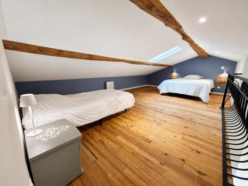 two beds in a bedroom with blue walls and wooden floors at Le petit repère in Jujurieux