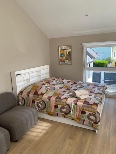 a bedroom with a bed and a chair and a window at Le nid d'Eve - studio cosy près de Strasbourg avec piscine in Illkirch-Graffenstaden