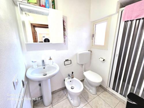a white bathroom with a toilet and a sink at La Casetta in Sarroch