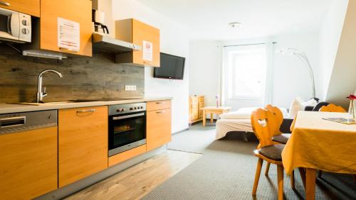 une cuisine avec des placards en bois et une salle à manger avec une table dans l'établissement Cityhouse Apartments Schladming, à Schladming