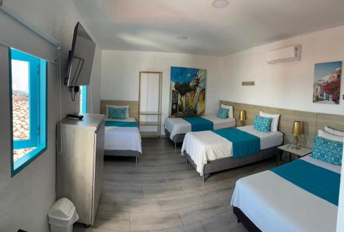 a hotel room with three beds and a flat screen tv at Hotel Aldea Plaza in Doradal