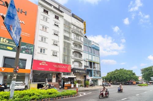 two people riding motorcycles down a street in front of a building at MÊ KÔNG HOTEL - Hotel H79 in Ho Chi Minh City