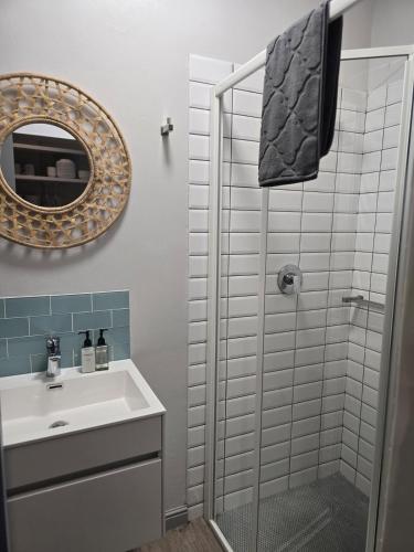 a bathroom with a shower and a sink and a mirror at Still in Struisbaai