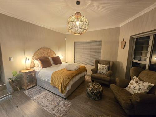 a bedroom with a bed and a chair and a chandelier at Still in Struisbaai