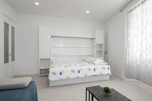 a white bedroom with a bed and a table at Apartma Svetlo udobje v Piranu - Bright Comfort Apartment in Piran in Piran