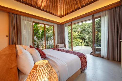 a bedroom with a large bed and large windows at Apittoya Villas in Gianyar