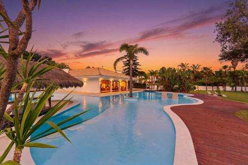 a resort swimming pool with a sunset in the background at Spot Troia - Boutique Suites in Troia